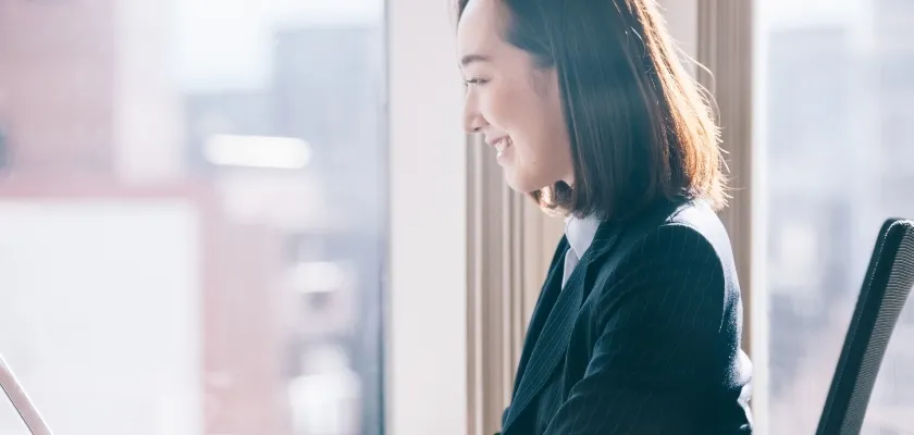 パソコン画面を見ながら笑顔で働く女性ビジネスパーソン