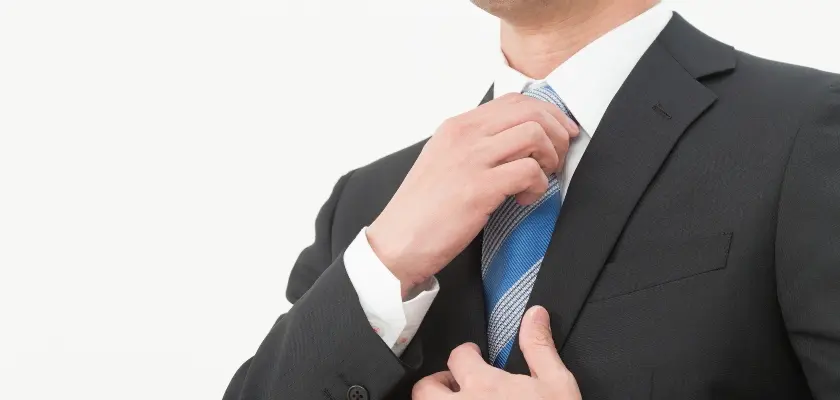 スーツ姿でネクタイを直す男性ビジネスパーソン