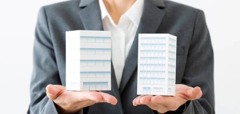 大企業と中小企業の模型を手に持つビジネスパーソン