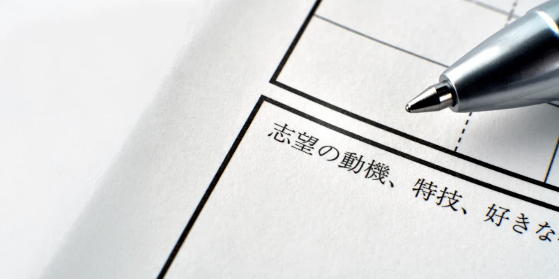 A close-up of a Japanese résumé form with a pen, showing the section for motivation and skills.