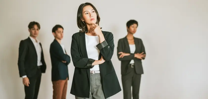 腕を組み真剣な表情を見せる女性と、後ろに立つ3人の同僚