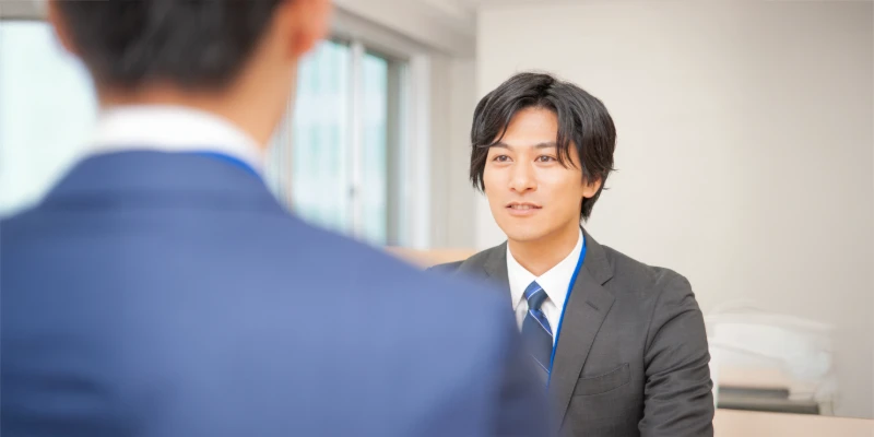 面接中に自信を持って話すスーツ姿の男性。