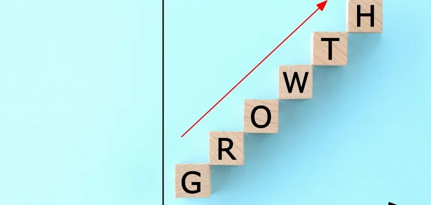 GROWTHと書かれた木のブロックが階段状に並び赤い矢印が上昇を示すシステムエンジニアの収入アップのイメージ