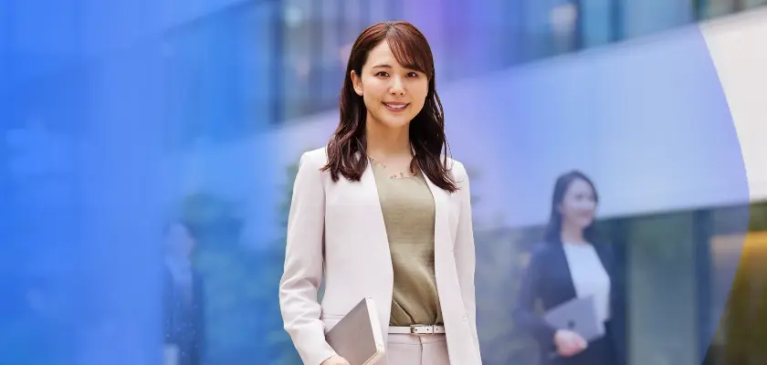 白いスーツ姿でタブレットを持つ女性ビジネスパーソン、オフィス街の背景
