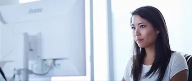 オフィスでデスクトップコンピューターに向かって作業する若い女性