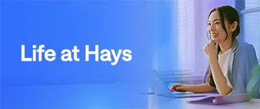 Young professional woman smiling at her desk with a laptop, showing life at Hays