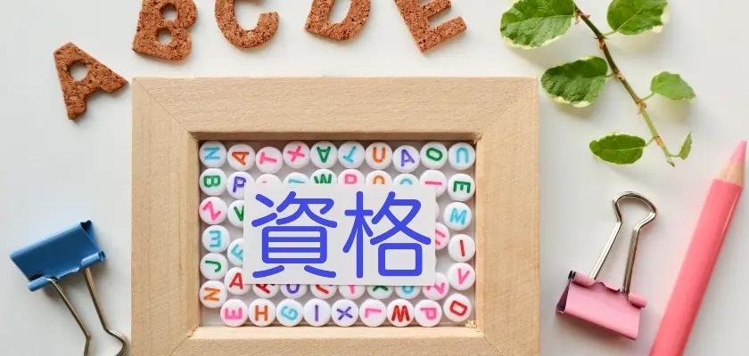 資格と書かれた額縁と文房具が並ぶカラフルなイメージ