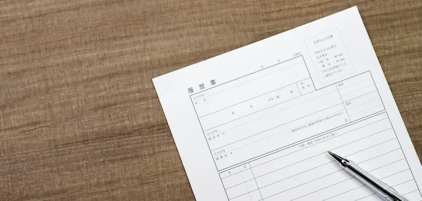 木目のデスクに置かれた履歴書とボールペン