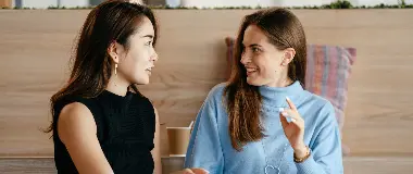 座って会話をしながら笑顔を見せる二人の女性