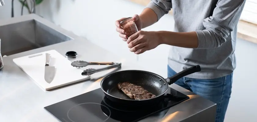 フライパンでステーキを調理する人の手元