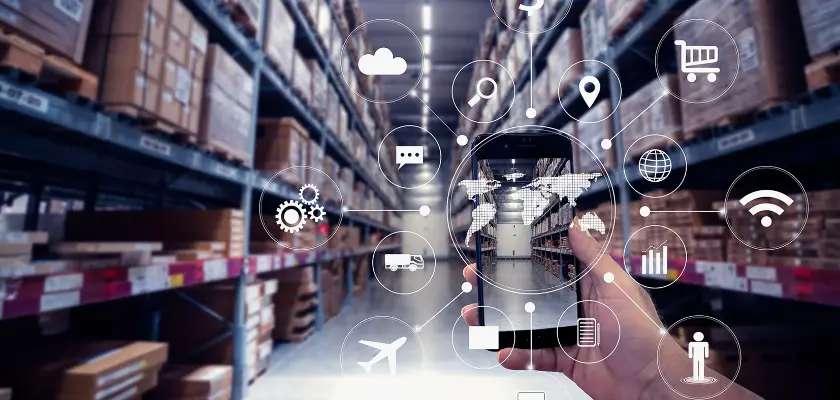 Hand holding a smartphone in a warehouse with digital technology icons representing logistics and supply chain management