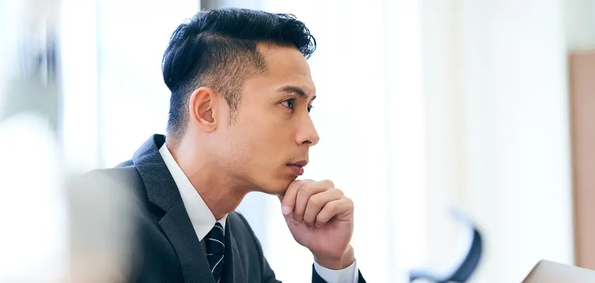 スーツ姿で真剣に考える男性ビジネスパーソン