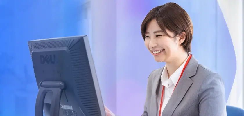 パソコンで仕事をする笑顔の女性 — オフィス職向け志望動機の書き方。